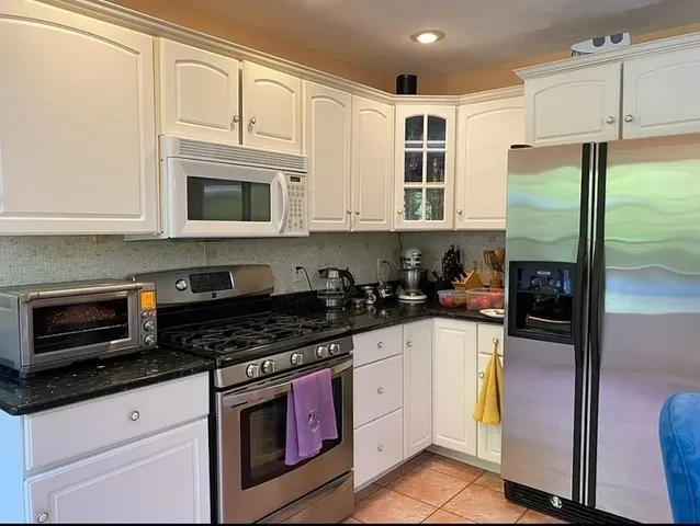 a kitchen with stainless steel appliances granite countertop a stove a refrigerator and a microwave