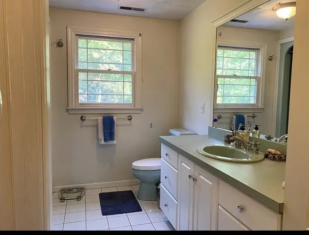 a bathroom with a granite countertop toilet a sink and a window