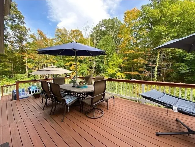 a view of deck with dinning table and chairs under an umbrella with wooden floor