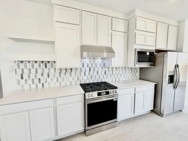 a kitchen with stainless steel appliances granite countertop a stove a sink and a refrigerator