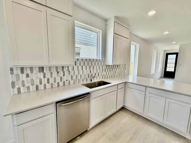 a kitchen with white cabinets and sink