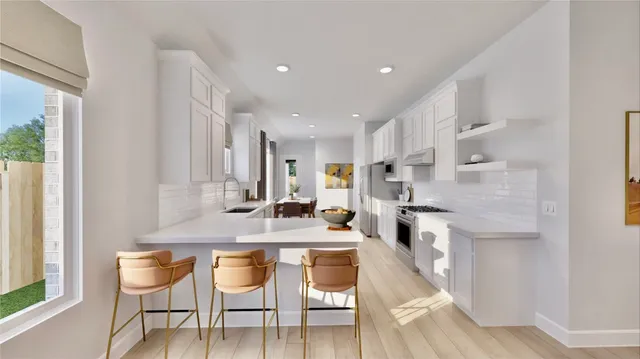 a kitchen with stainless steel appliances kitchen island granite countertop a dining table chairs and a refrigerator