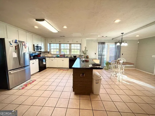 a kitchen with stainless steel appliances kitchen island granite countertop a refrigerator a stove a sink dishwasher and a dining table with wooden floor