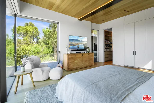 a bedroom with a bed a large window and walk in closet