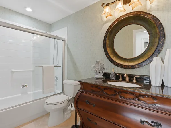 a bathroom with a granite countertop sink a toilet and shower