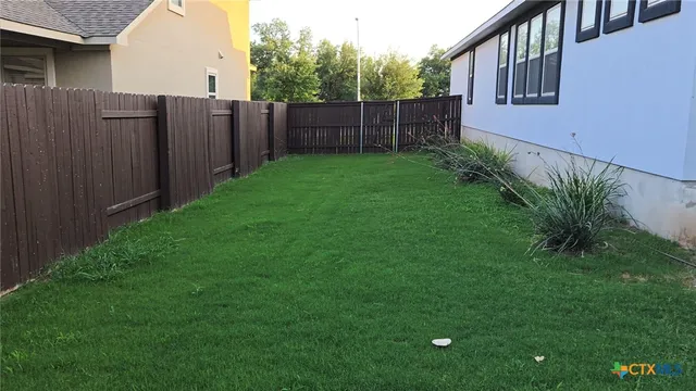 a view of a backyard with potted plants and wooden fence