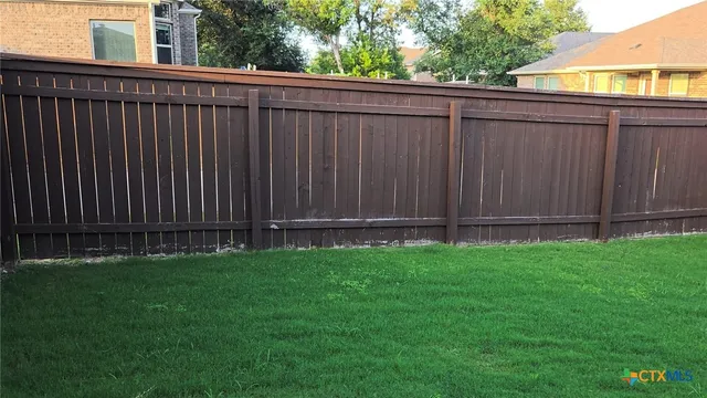 a view of a backyard with wooden fence