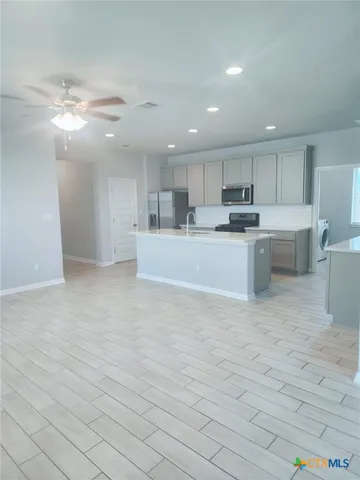 a large white kitchen with kitchen island a sink a stove a oven with a dining table and chairs