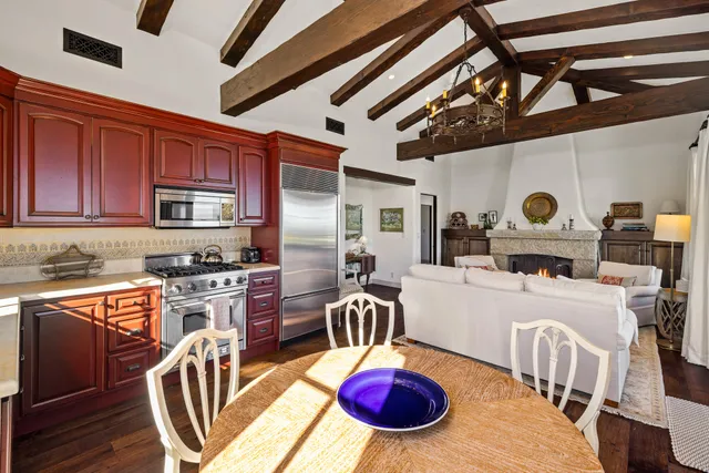 a kitchen with stainless steel appliances granite countertop a stove a refrigerator a microwave oven with a dining table and chairs