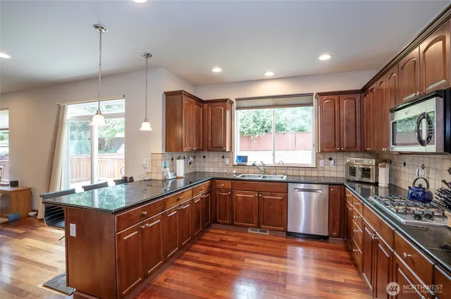 a kitchen with stainless steel appliances granite countertop wooden cabinets a sink dishwasher a stove and a refrigerator