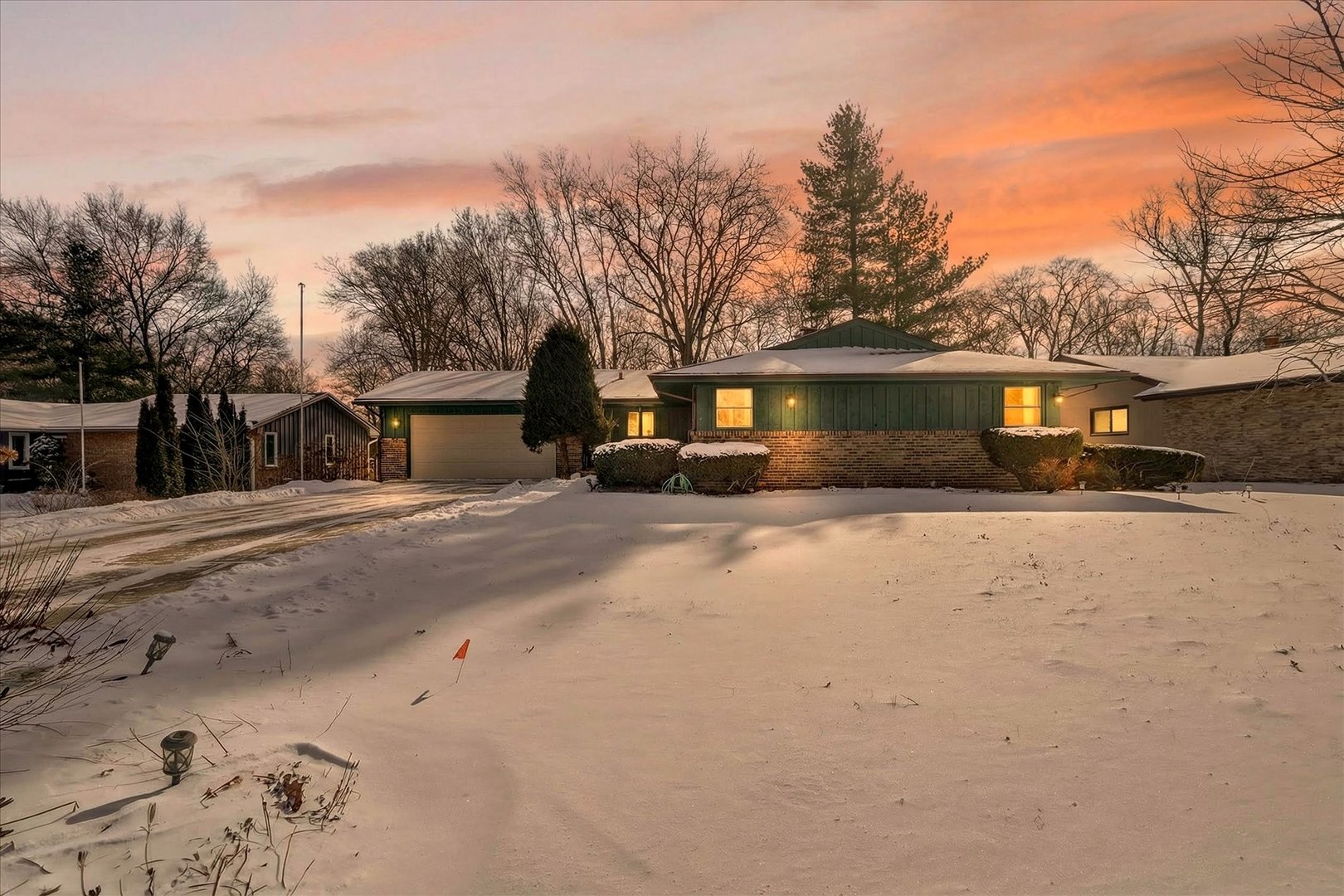 a front view of a house with a yard covered with snow