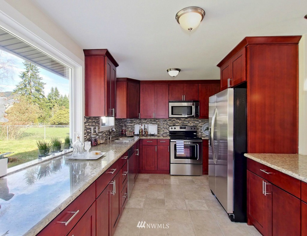 18430 Southeast 135th Street Renton, WA 98059 - Photo 5 of 13 a kitchen with stainless steel appliances granite countertop a refrigerator sink and stove