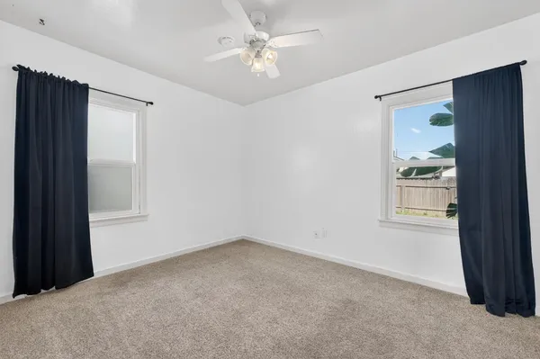 an empty room with windows and fan