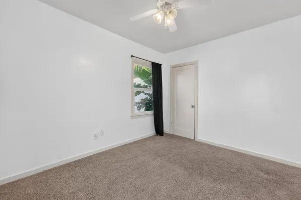 an empty room with a chandelier fan and windows