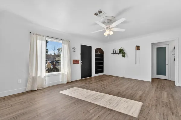 a view of an empty room with window and wooden floor
