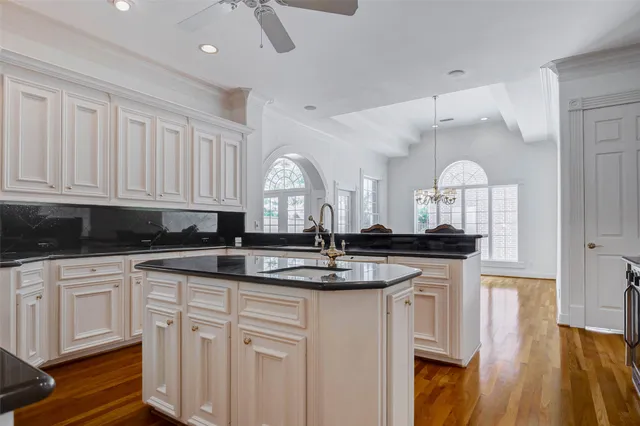 a kitchen with stainless steel appliances granite countertop a sink a stove and white cabinets
