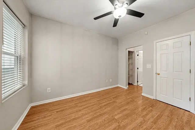 a view of empty room with wooden floor and fan