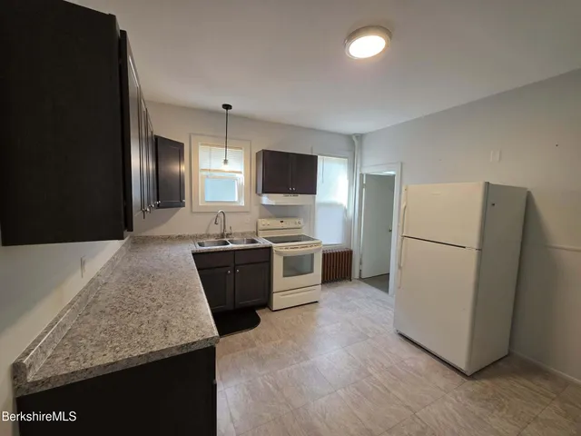 a large kitchen with a refrigerator a sink a stove and microwave