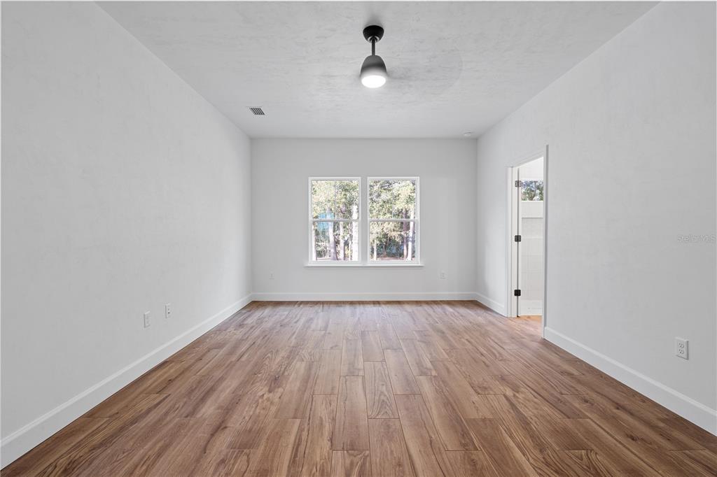 601 Fisher Drive Bronson, FL 32621 - Photo 12 of 32 an empty room with wooden floor chandelier fan and windows