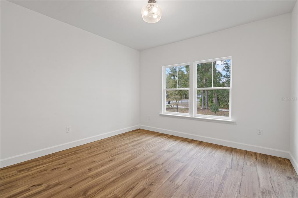 601 Fisher Drive Bronson, FL 32621 - Photo 21 of 32 an empty room with wooden floor and windows