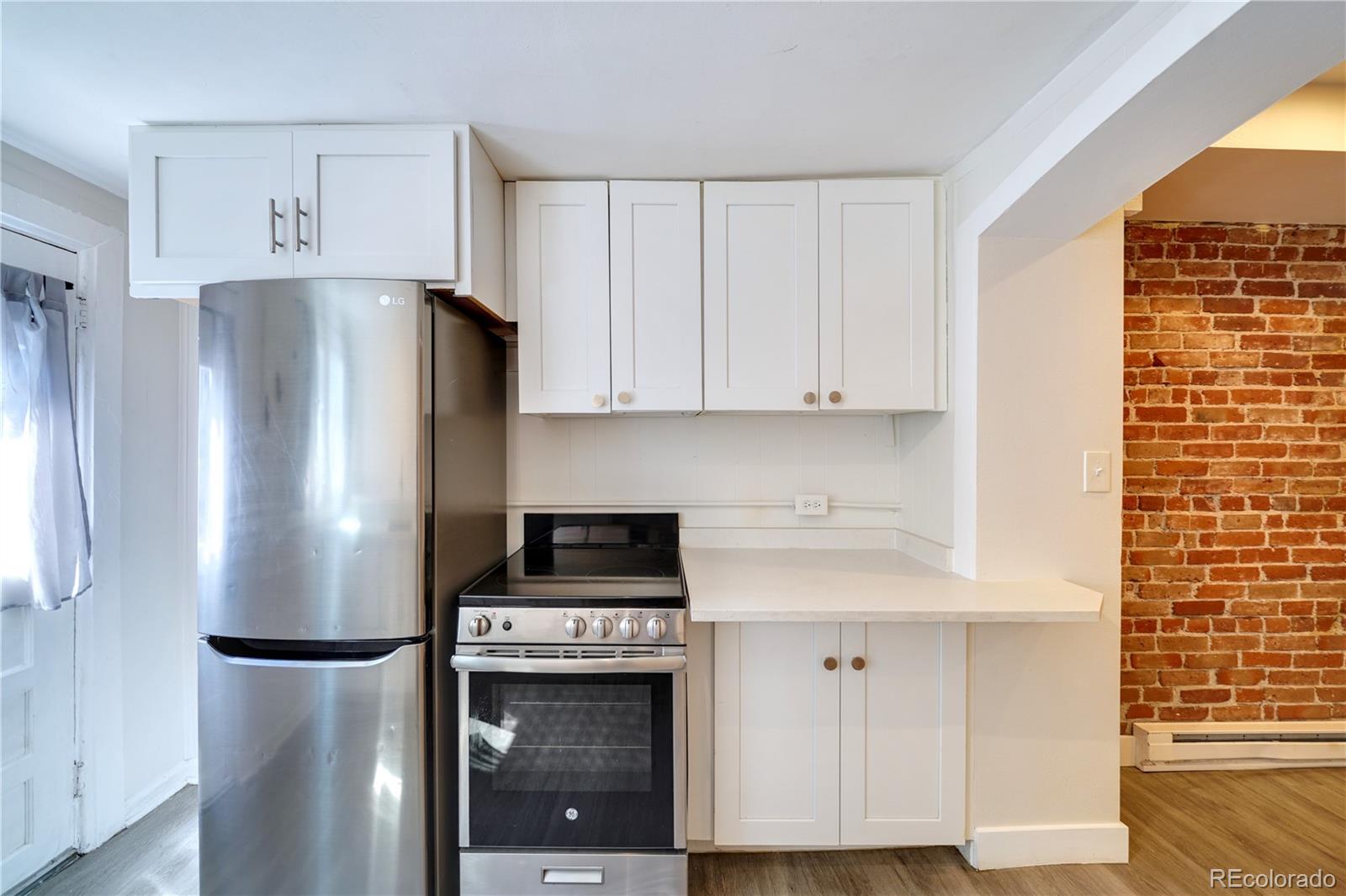 2528 West 23rd Avenue, Unit B Denver, CO 80211 - Photo 5 of 11 a kitchen with stainless steel appliances a refrigerator a stove and cabinets