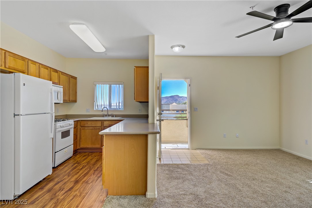 2291 West Horizon Ridge Parkway, Unit 11266 Henderson, NV 89052 - Photo 14 of 40 Kitchen featuring white appliances, light countertops, brown cabinetry, and a peninsula