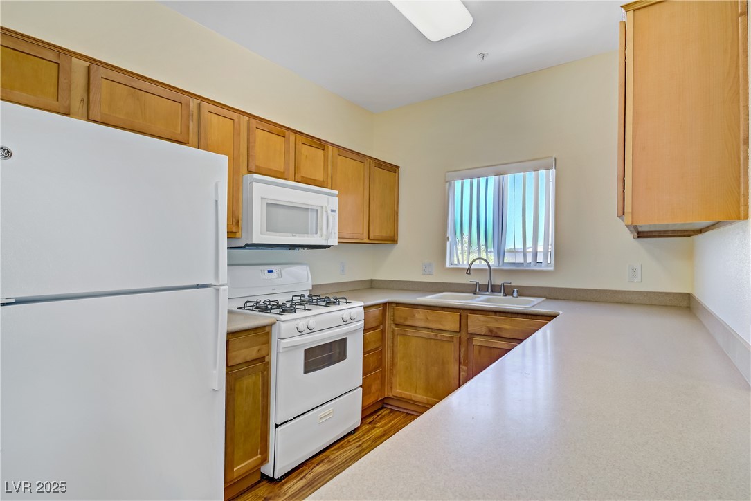 2291 West Horizon Ridge Parkway, Unit 11266 Henderson, NV 89052 - Photo 16 of 40 Kitchen with white appliances, light countertops, and brown cabinetry