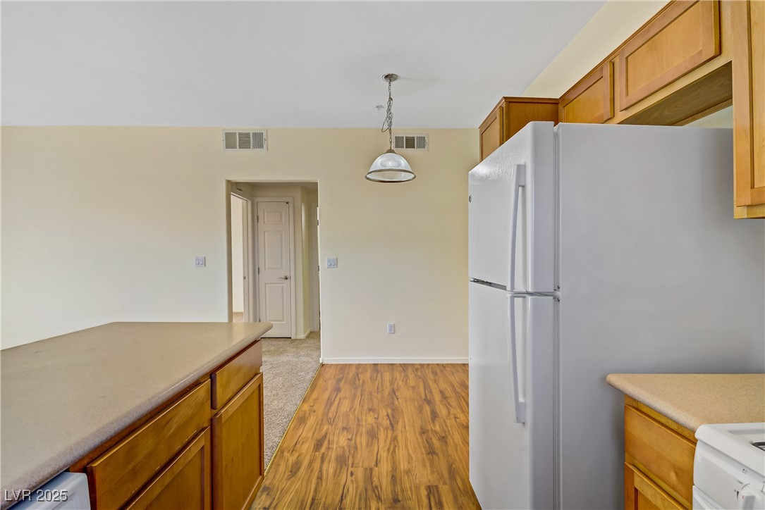 2291 West Horizon Ridge Parkway, Unit 11266 Henderson, NV 89052 - Photo 18 of 40 Kitchen featuring brown cabinets, light wood-style flooring, light countertops, decorative light fixtures, and white range