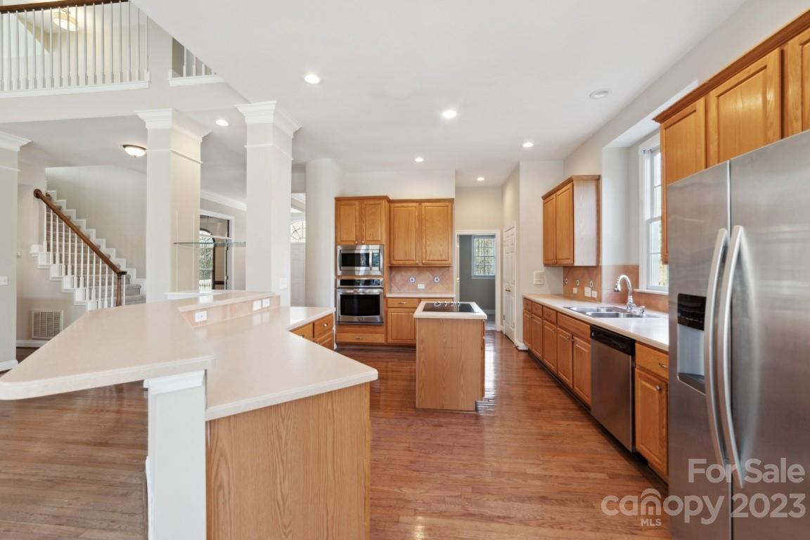 8403 Royster Run Waxhaw, NC 28173 - Photo 9 of 25 a large kitchen with stainless steel appliances kitchen island granite countertop a large kitchen island a stove a refrigerator a sink and dishwasher with wooden floor
