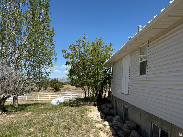 10000 North 6730th East Spring City, UT 84662 - Photo 28 of 31 Exterior siding with a white metal roof, featuring a rock retaining wall and several ground-level windows
