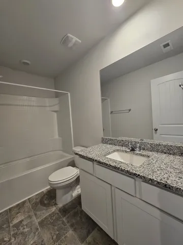 a bathroom with a granite countertop toilet a sink and a mirror