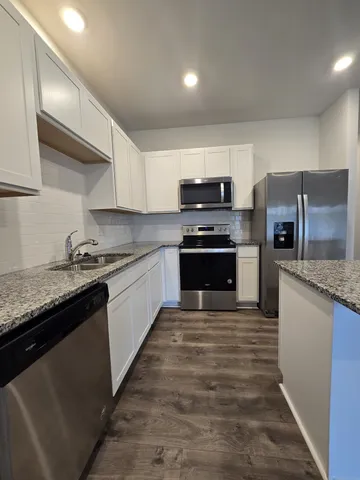 a large kitchen with stainless steel appliances granite countertop a stove top oven a sink and dishwasher