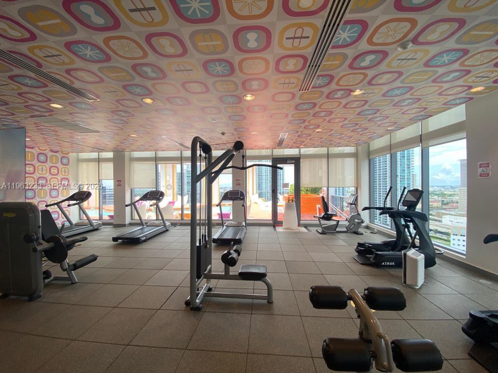 31 Southeast 6th Street, Unit 1404 Miami, FL 33131 - Photo 8 of 13 a gym room with gym equipment and a large window