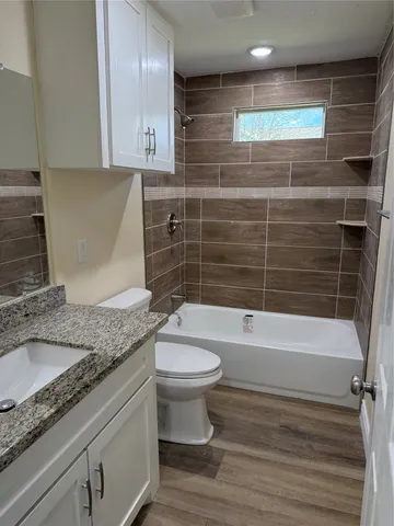 a bathroom with a granite countertop sink a toilet and bathtub