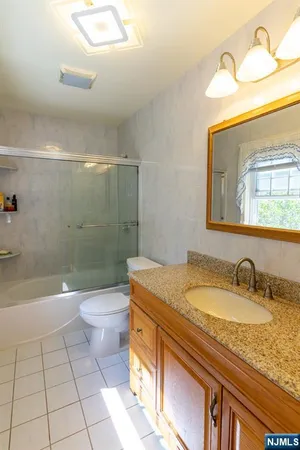 a bathroom with a granite countertop sink a toilet a mirror and bathtub