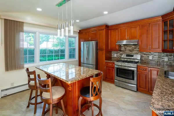 a kitchen with stainless steel appliances granite countertop wooden floor dining table and chairs