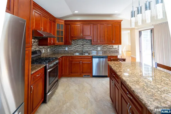 a kitchen with stainless steel appliances granite countertop a stove a sink and a refrigerator