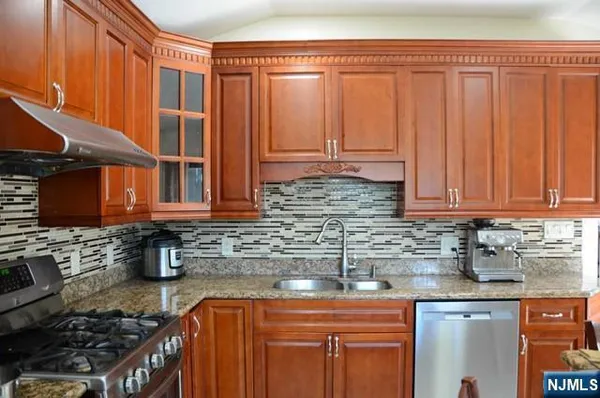 a kitchen with stainless steel appliances granite countertop a sink a stove and cabinets