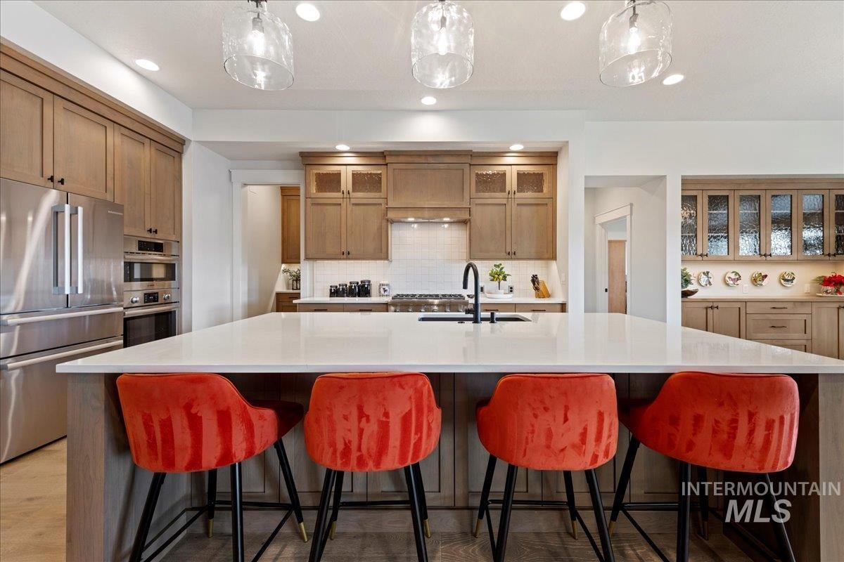 280 North Boulder Rdg Way Eagle, ID 83616 - Photo 14 of 50 Kitchen featuring stainless steel appliances, glass insert cabinets, decorative backsplash, a breakfast bar, and recessed lighting