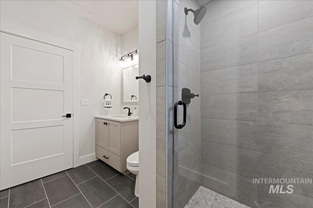 280 North Boulder Rdg Way Eagle, ID 83616 - Photo 22 of 50 Bathroom with vanity, dark tile patterned floors, and a shower stall