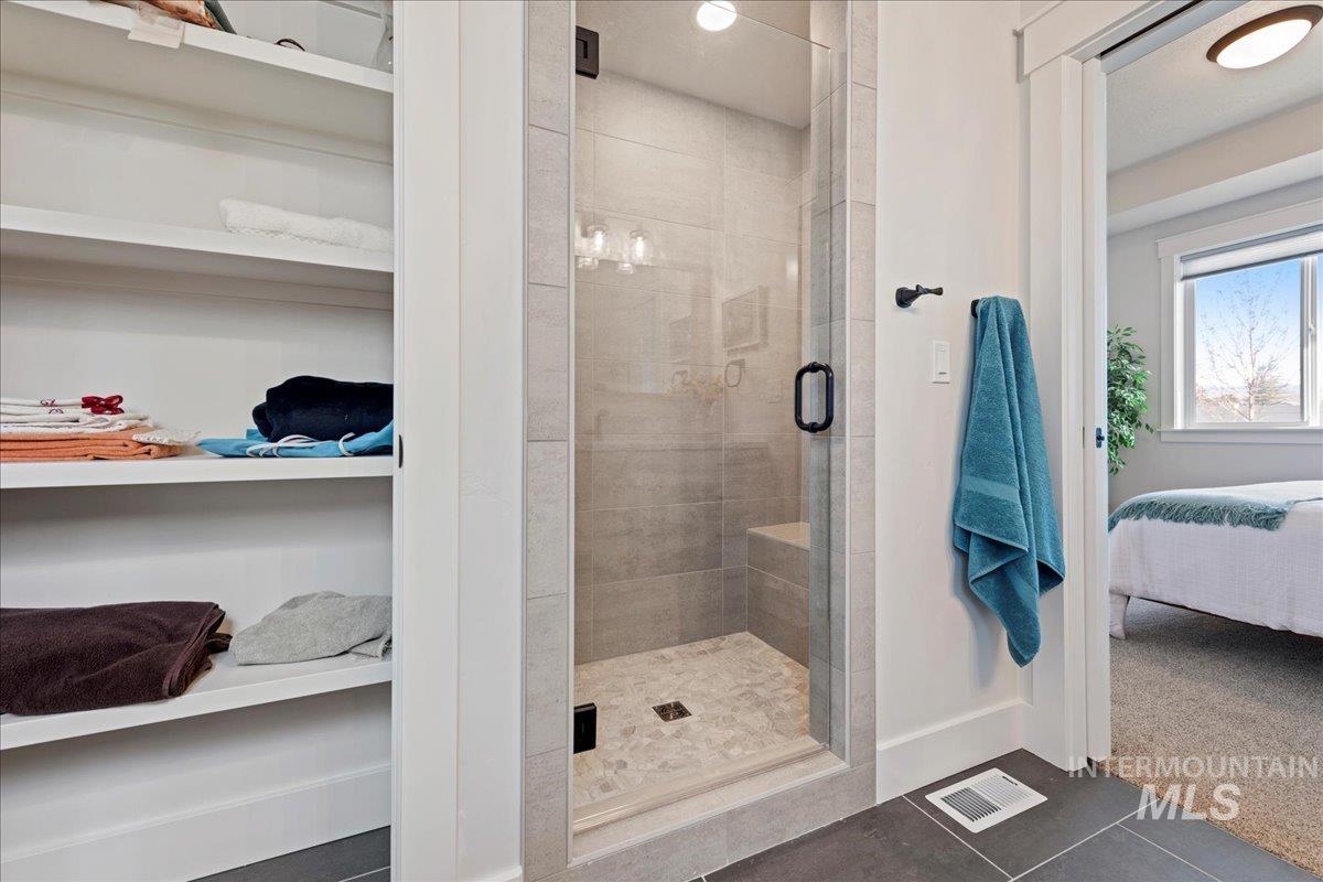 280 North Boulder Rdg Way Eagle, ID 83616 - Photo 30 of 50 Bathroom with a stall shower, dark tile patterned flooring, connected bathroom, and dark colored carpet