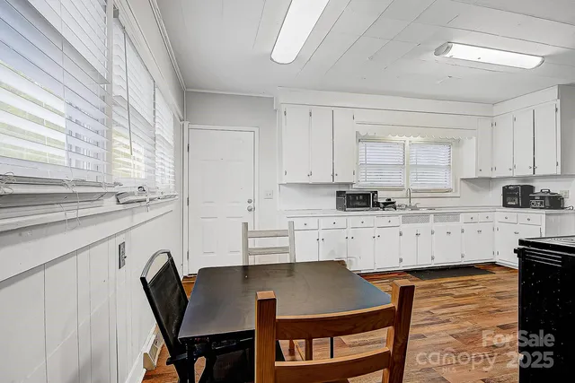 a kitchen with stainless steel appliances granite countertop a table chairs sink and cabinets