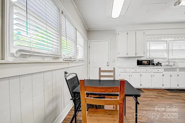 a kitchen with stainless steel appliances kitchen island granite countertop a table chairs sink and cabinets