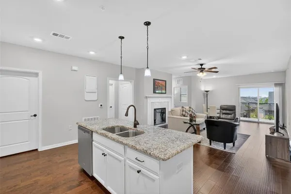 a kitchen island with granite countertop a sink cabinets and wooden floor