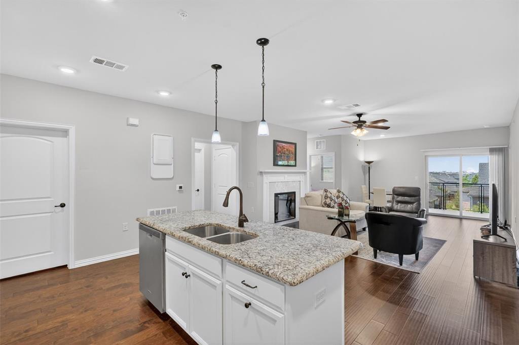 651 Watters Road, Unit 5305 Allen, TX 75013 - Photo 1 of 40 a kitchen island with granite countertop a sink cabinets and wooden floor