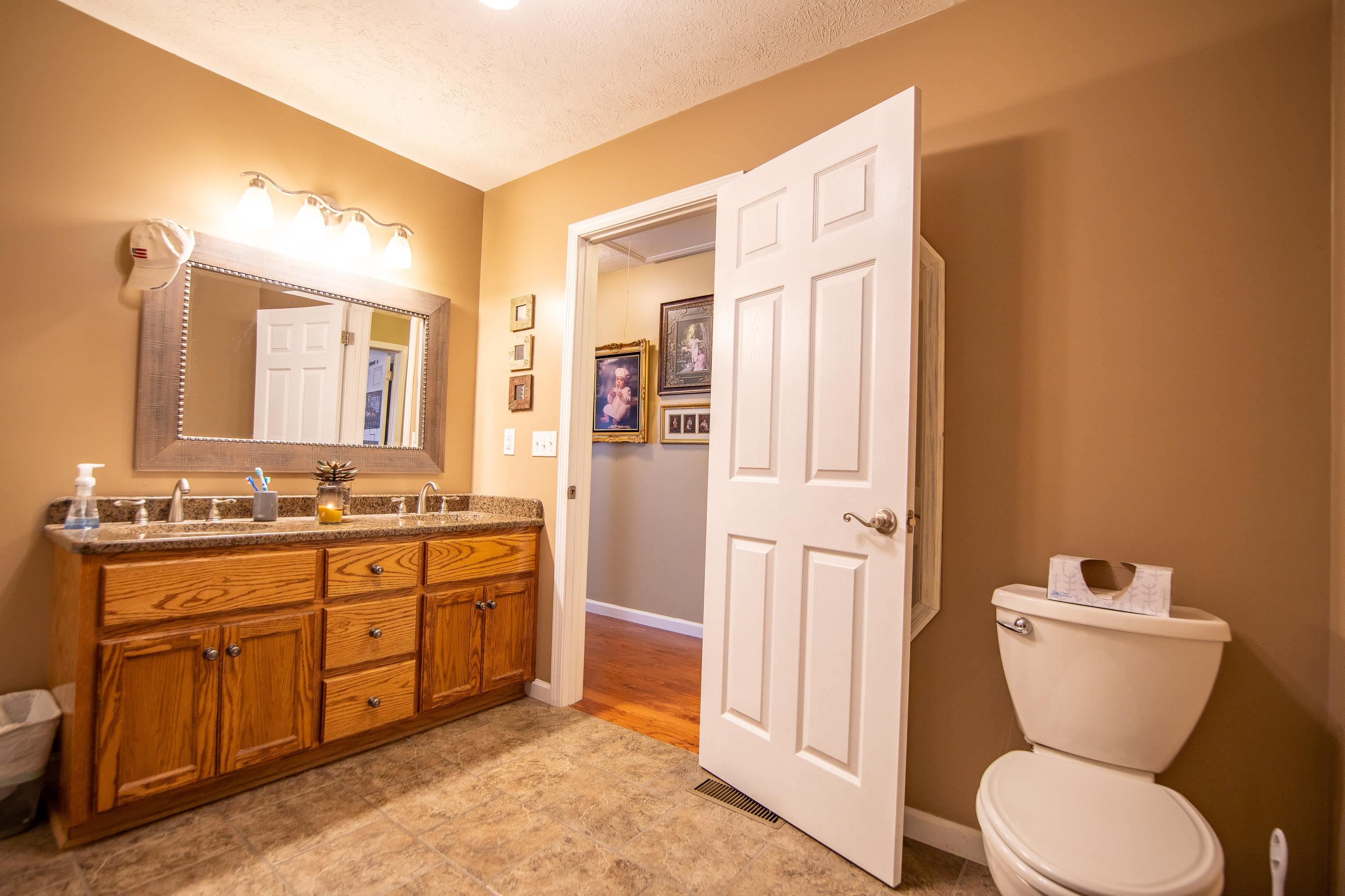6843 Michie Pebble Hill Road Michie, TN 38357 - Photo 13 of 25 a bathroom with a granite countertop toilet sink and mirror