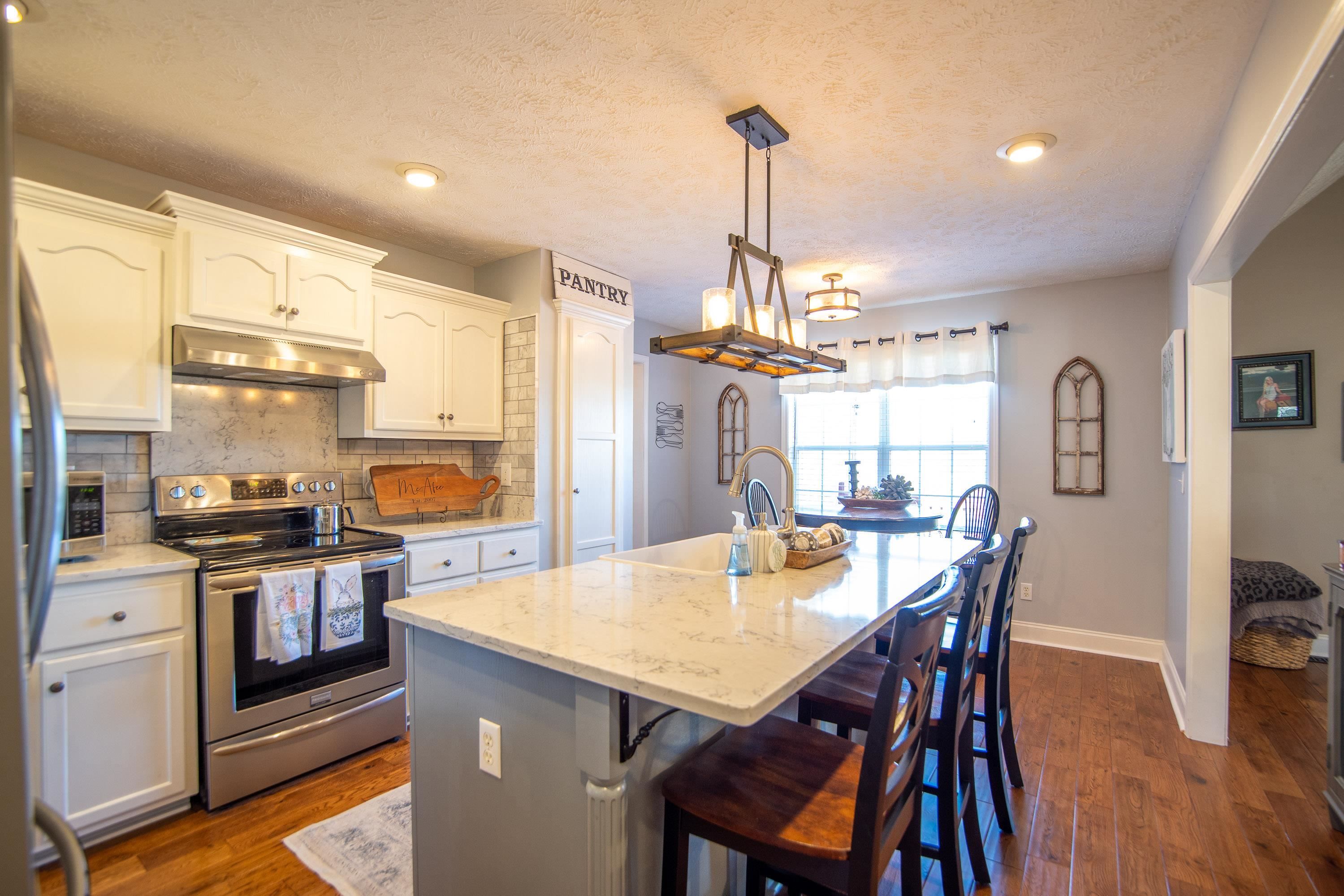 6843 Michie Pebble Hill Road Michie, TN 38357 - Photo 2 of 25 a kitchen with stainless steel appliances kitchen island granite countertop a table chairs stove and refrigerator