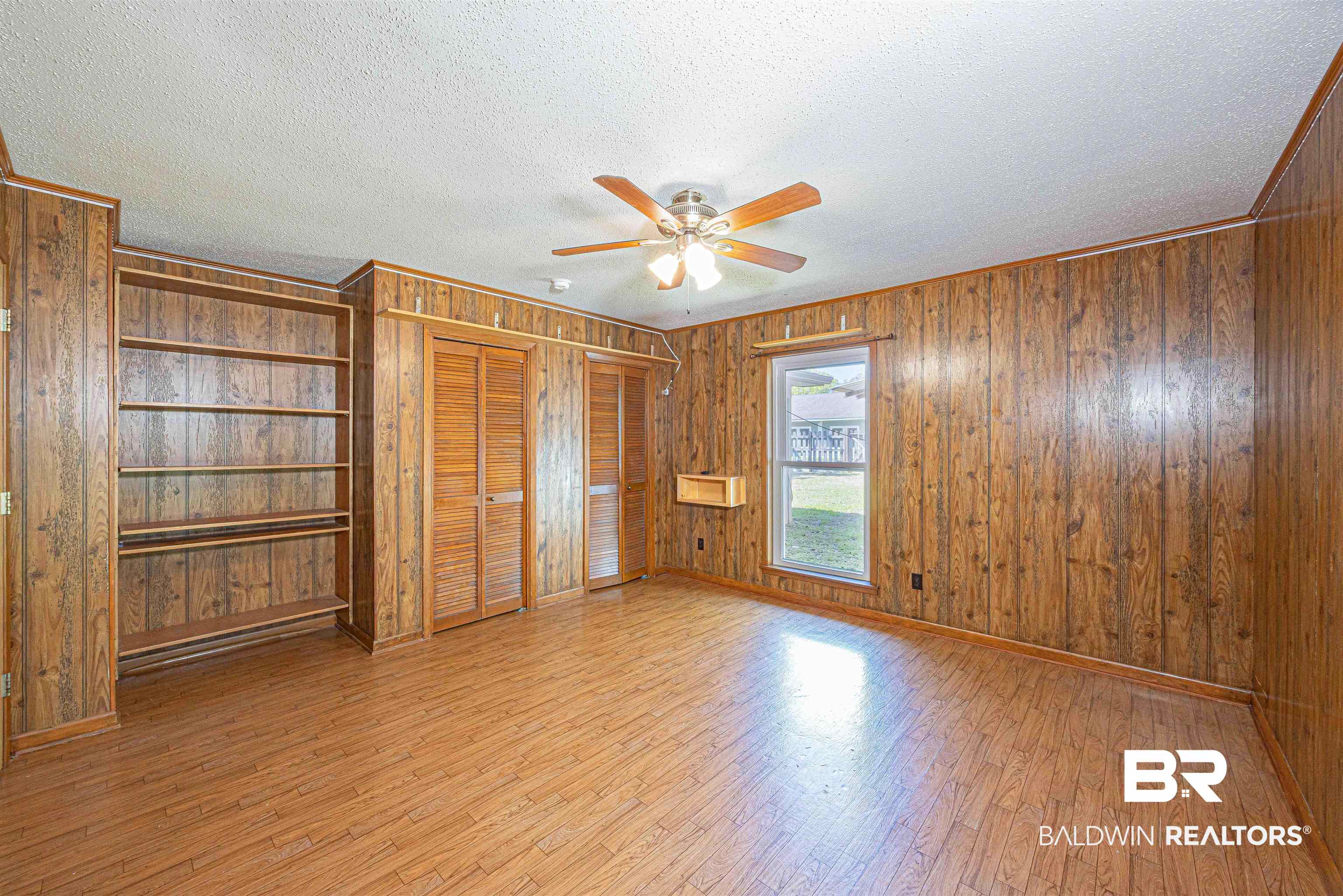43101 Brown Road Bay Minette, AL 36507 - Photo 45 of 81 Unfurnished bedroom with wood walls, wood finished floors, a textured ceiling, multiple closets, and ceiling fan