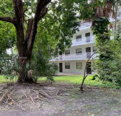 a view of a house with a yard and large trees