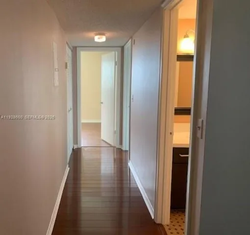 a view of a hallway with wooden floor and a bathroom